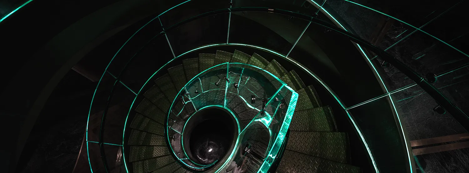 A futuristic spiral staircase with green lighting, made of metal, in a modern building