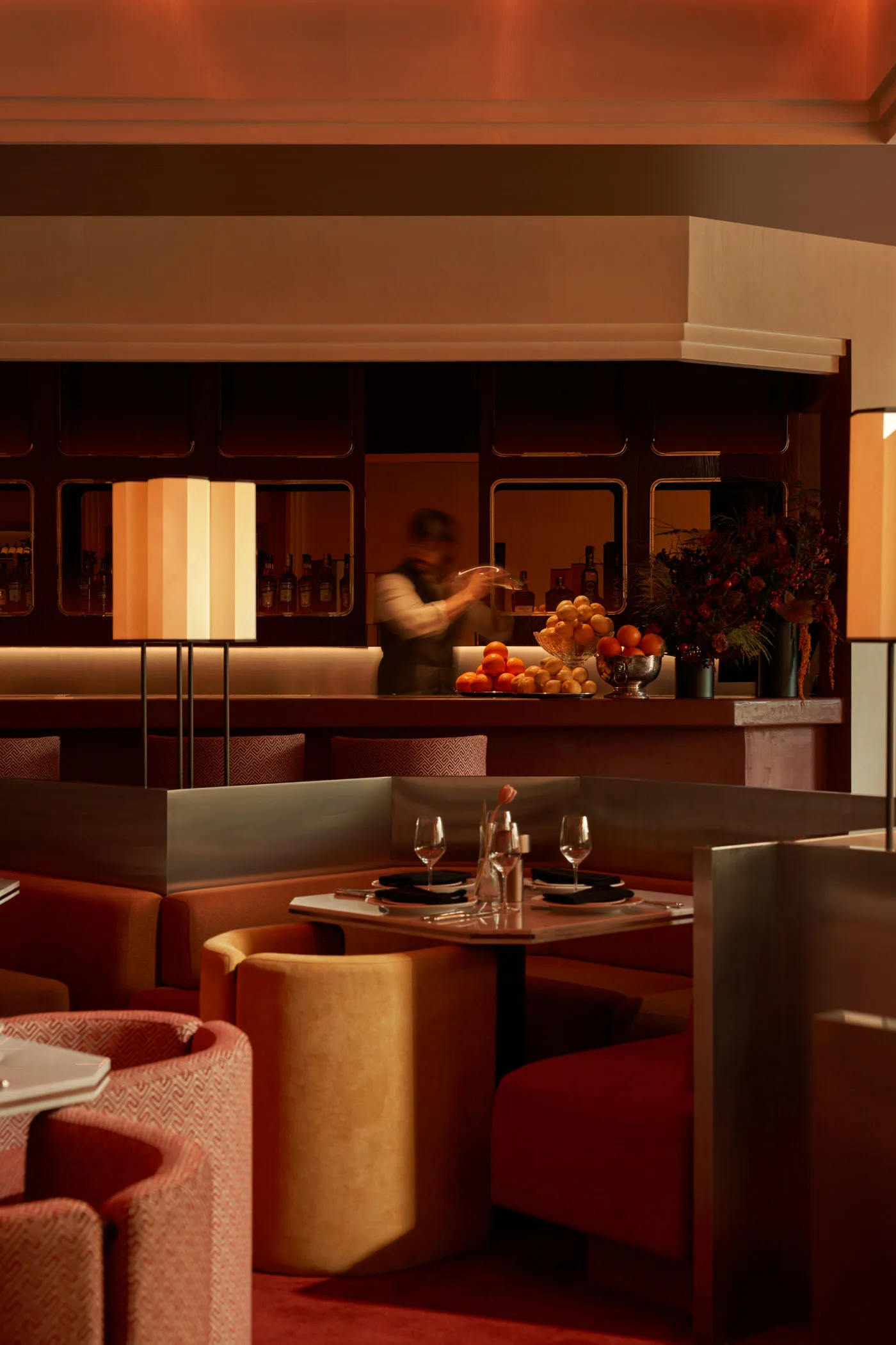 Sophisticated restaurant interior with a bar, dining tables, and wine glasses, set for dinner service