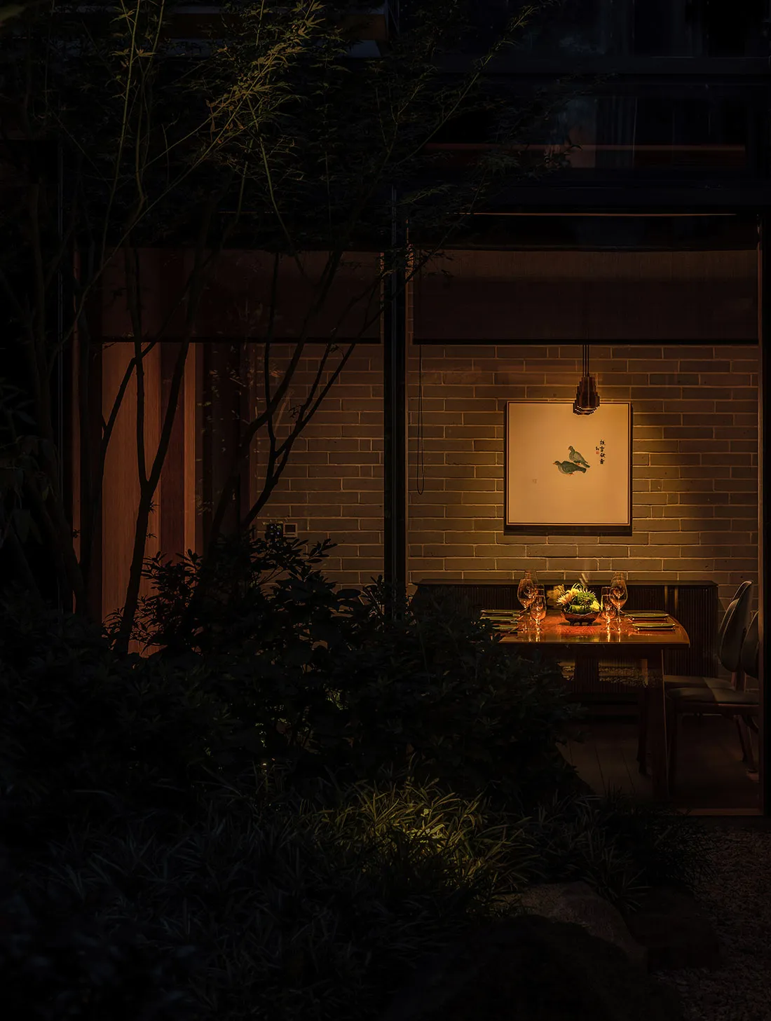 Cozy Asian dining area with a brick wall, a table, and chairs, featuring wine glasses and a warm atmosphere