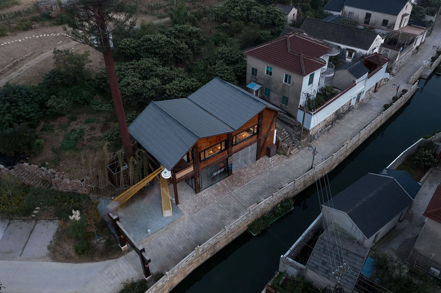 棟建於樹木環繞的架空房屋，具木構結構與多扇窗戶引入自然光線，坐落於寧靜祥和的環境中