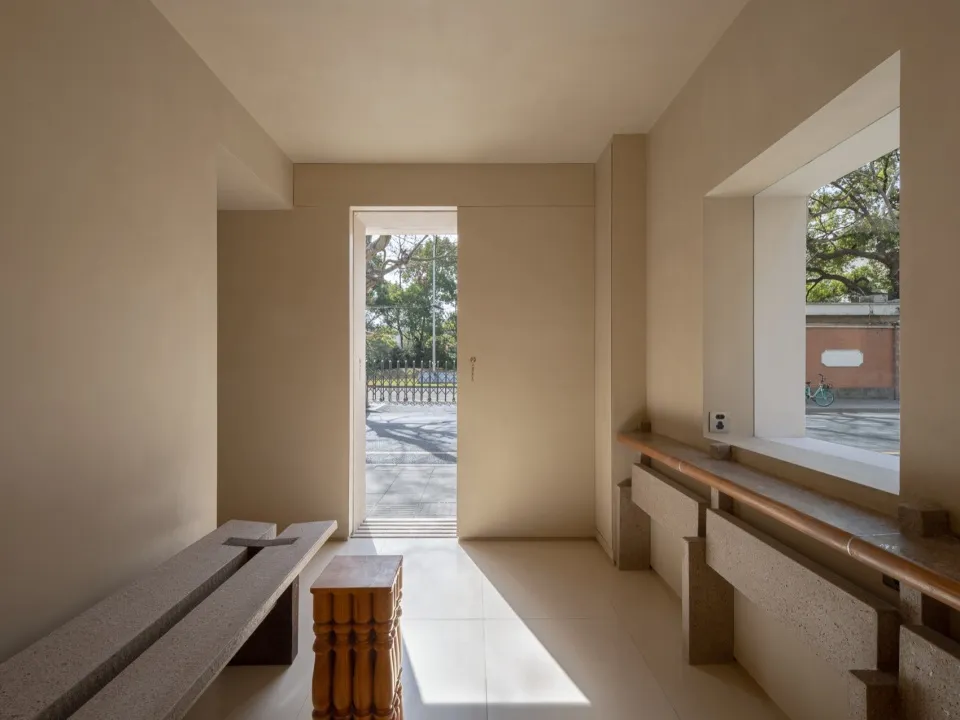 Empty open-plan living area with white walls, a doorway to another room, and benches in both spaces
