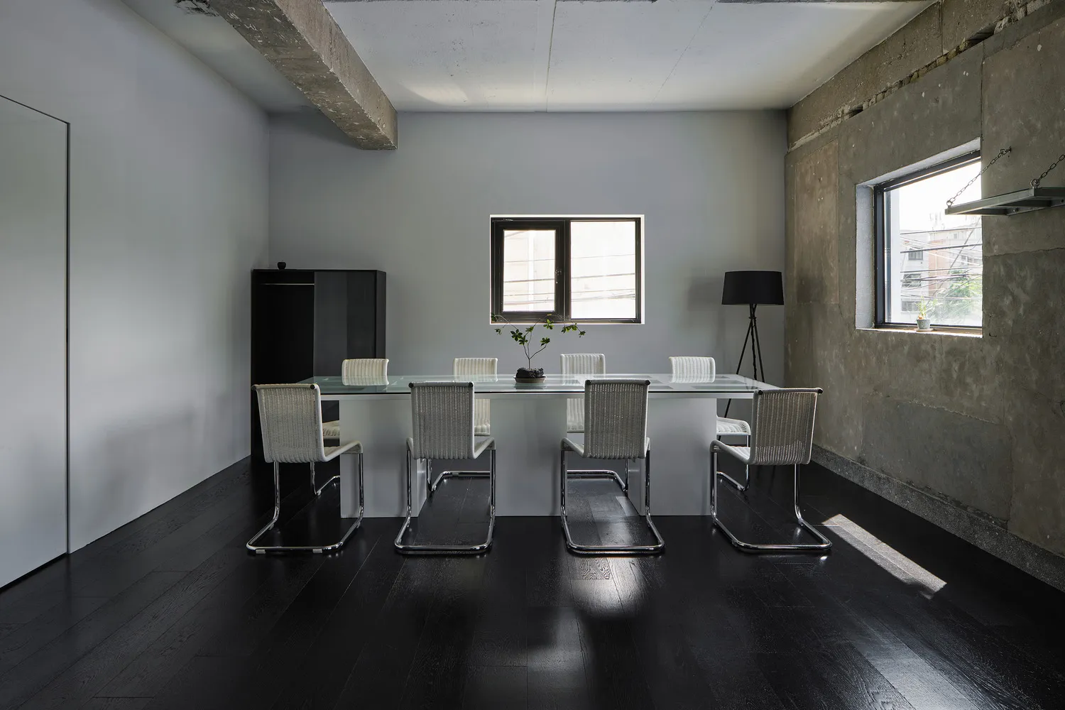 Empty modern dining room with a glass table surrounded by six chairs, black floor, and white walls