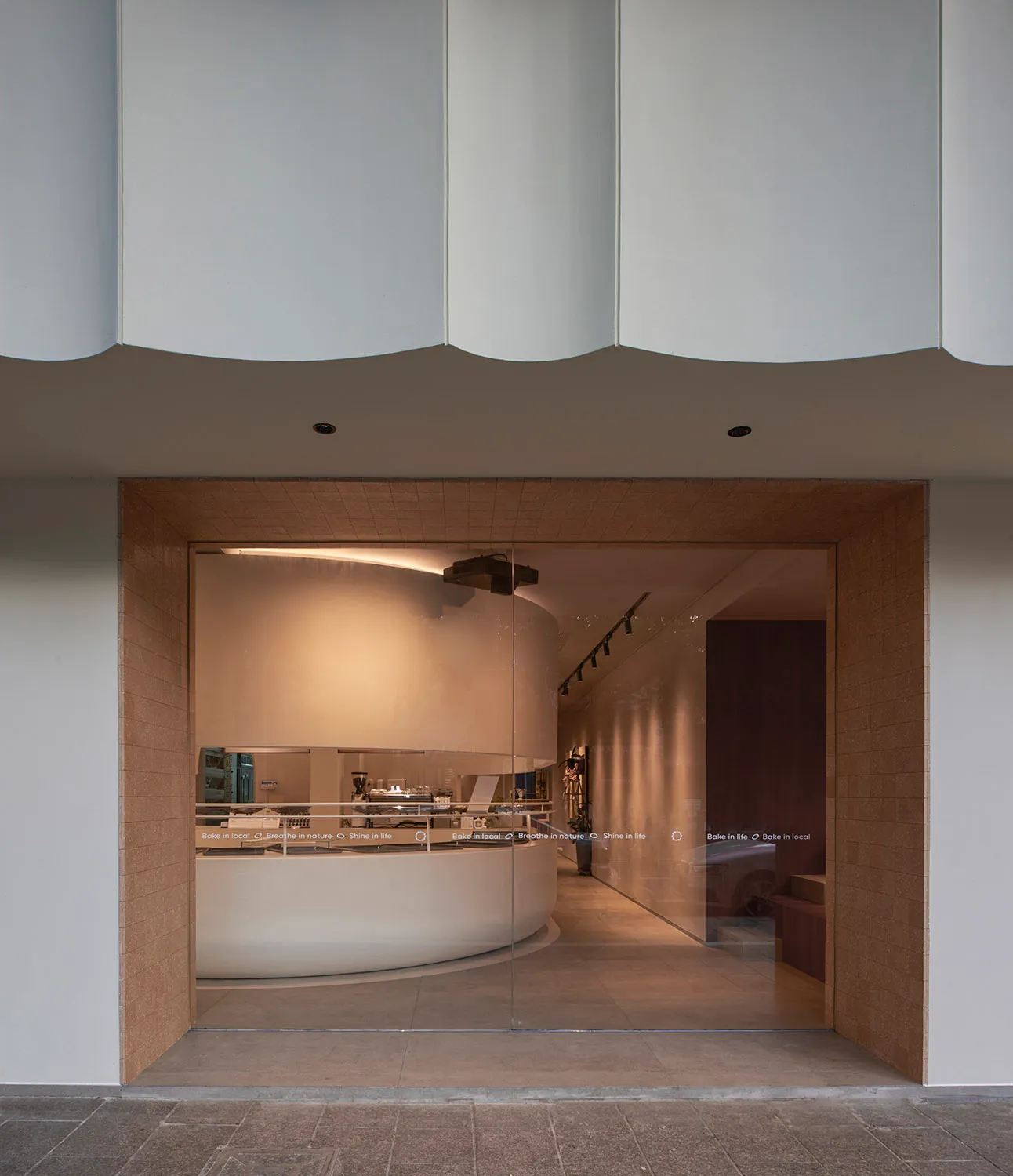 A restaurant interior with a circular dining area, curved wall, and chairs around a large dining table, creating an inviting atmosphere