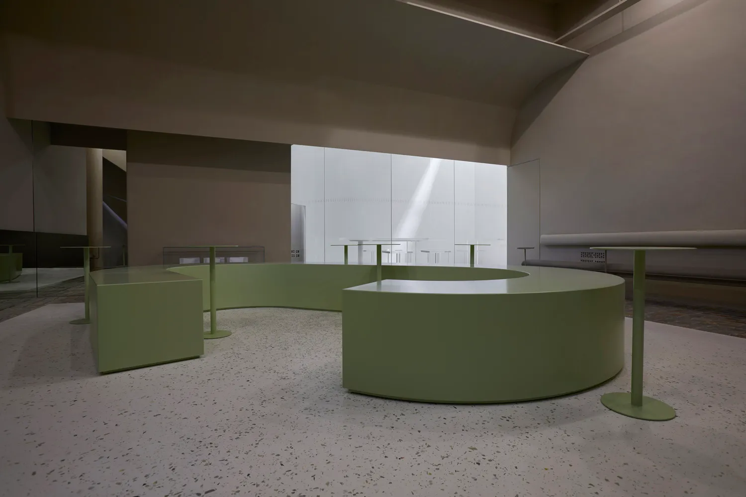 A modern cafe with green tables and chairs, white walls, and a clean, bright atmosphere