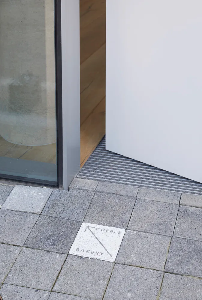 A traditional hallway entrance with a wooden floor, a doorway, and a sign indicating the direction to the hallway