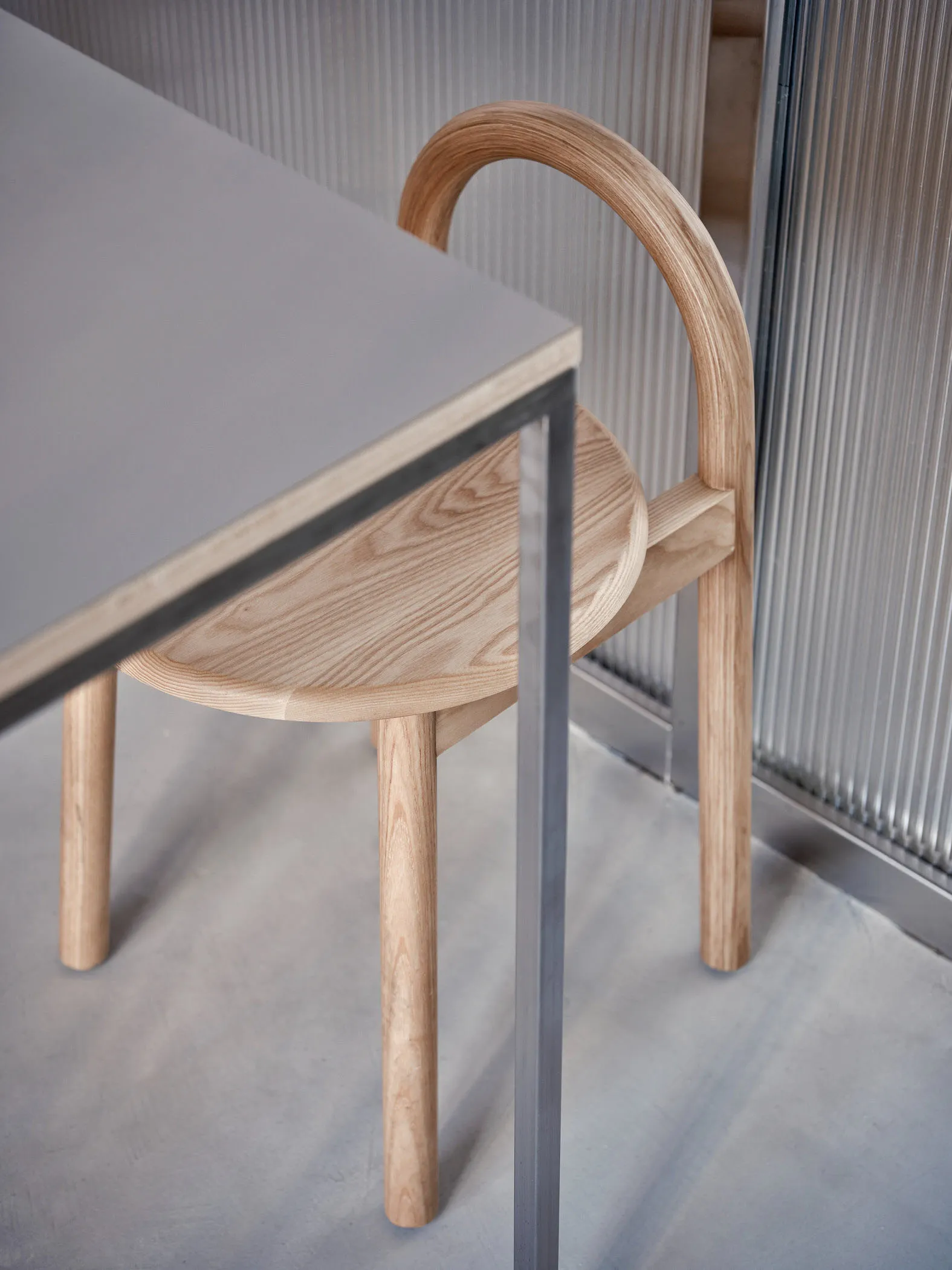 A cozy indoor space with a wooden chair on a grey carpet in front of a table, featuring a modern metal-framed chair