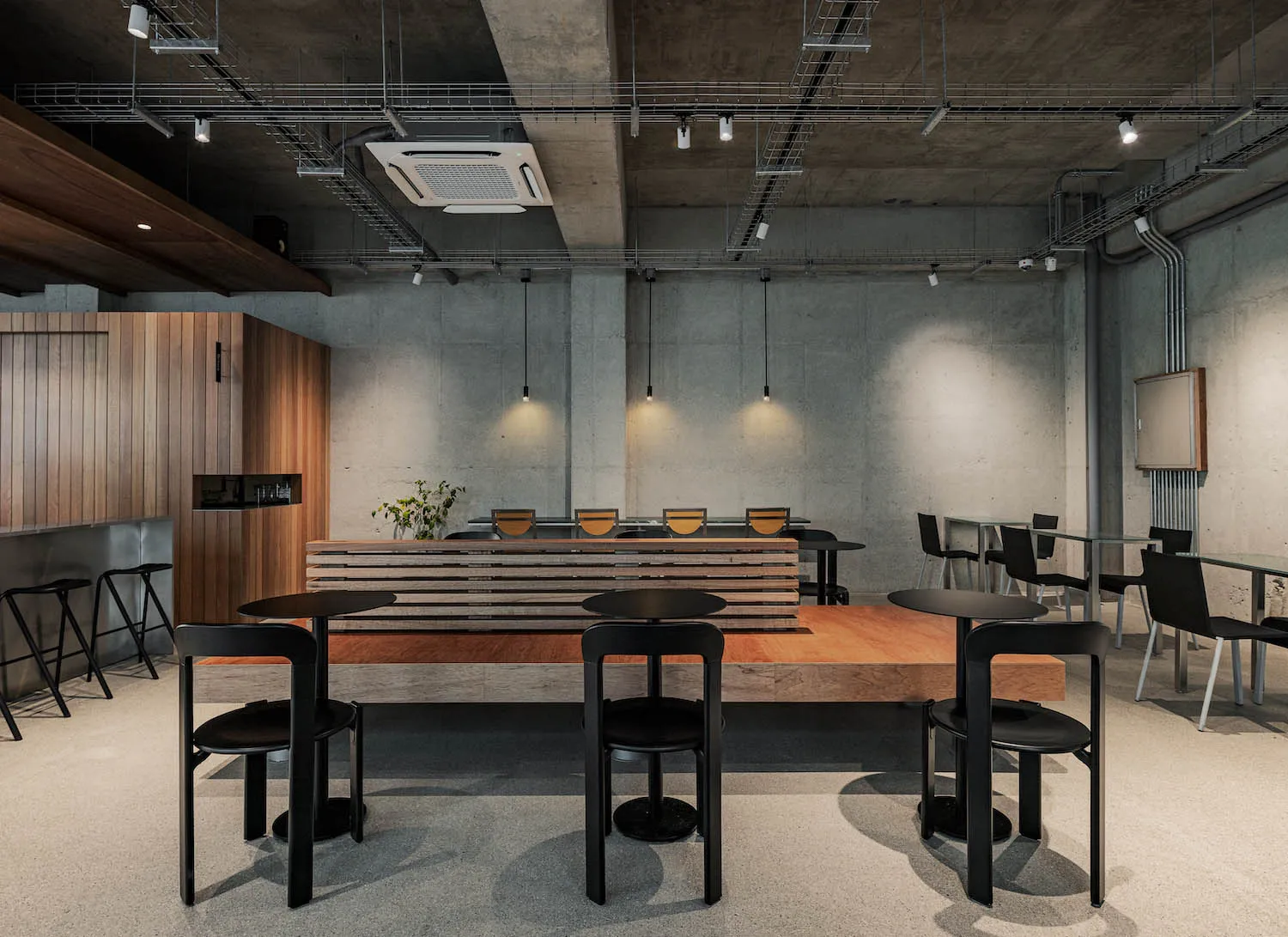 Empty modern restaurant with concrete walls and floors, tables, chairs, and bowls, creating a clean and inviting dining environment