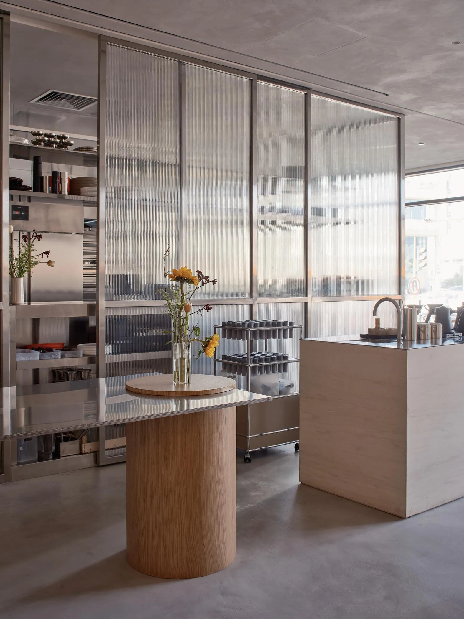 Open kitchen with a wooden island, a vase of flowers, books, and bottles, creating a clean and welcoming atmosphere