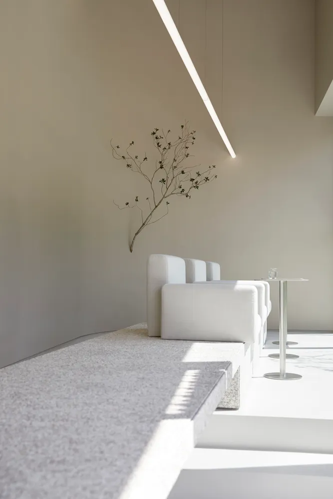 A calm and inviting living space with a white couch, two chairs, and a tree sculpture on the wall, all made of fabric, in a warm and comfortable atmosphere
