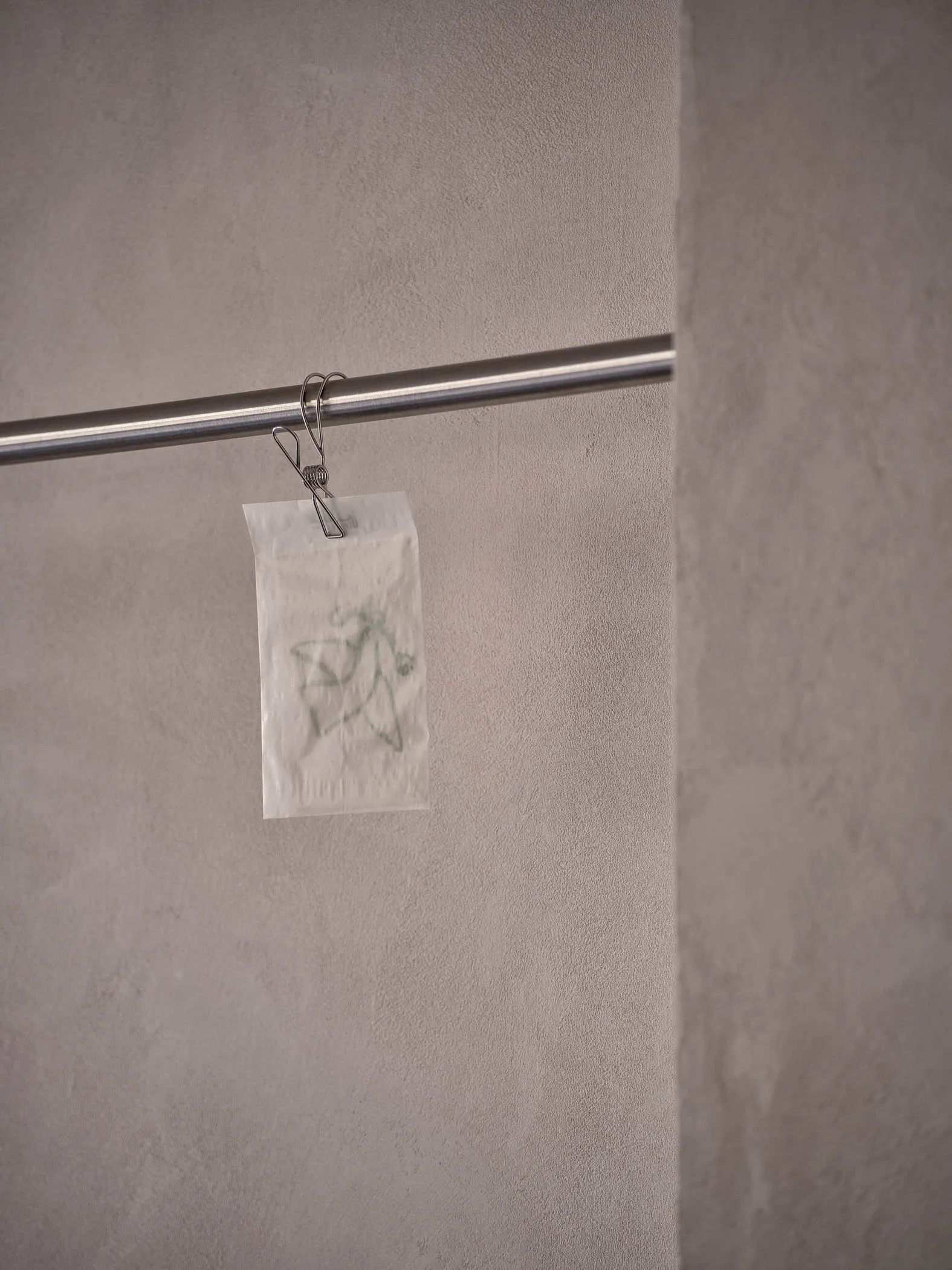 A dirty bathroom with a toilet paper holder and two rolls of toilet paper, with visible dirt on the walls