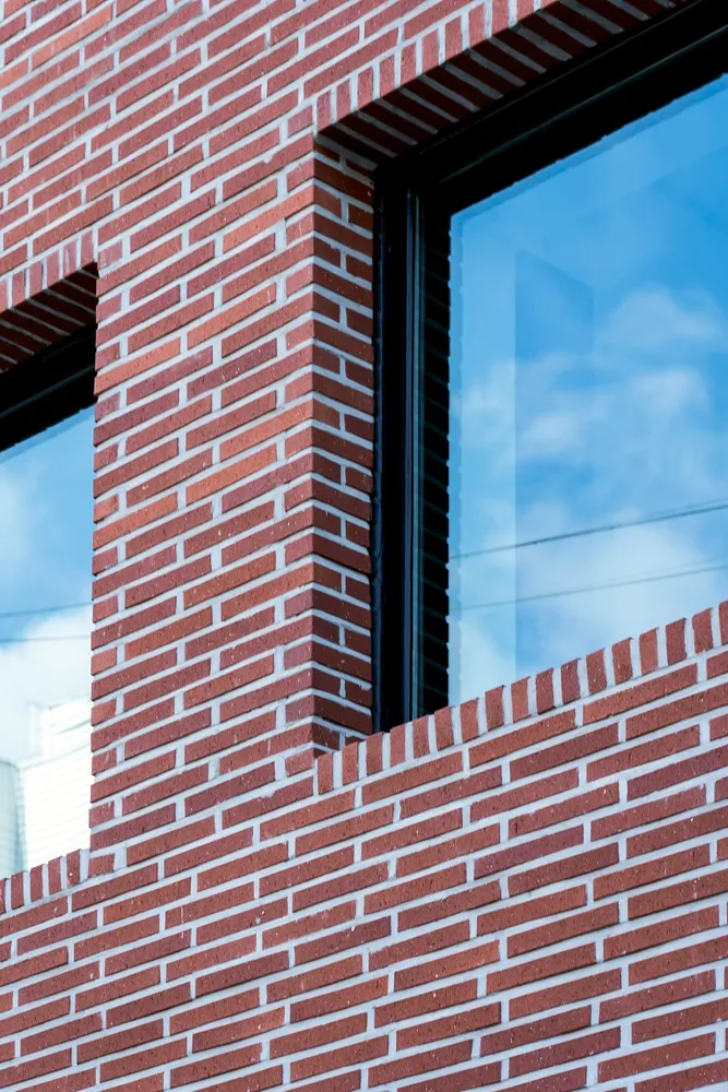 A traditional brick building with a glass window on its side, allowing natural light to enter, giving a sturdy and classic appearance