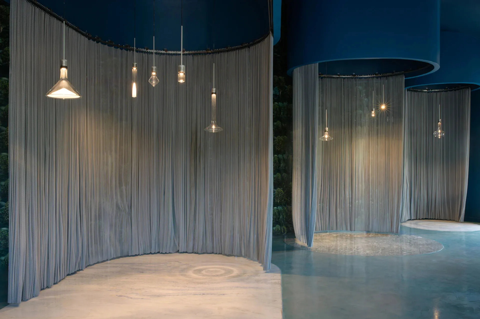 An indoor space with two curtain walls and hanging lights between them, featuring soft and elegant fabric curtains and a sophisticated atmosphere