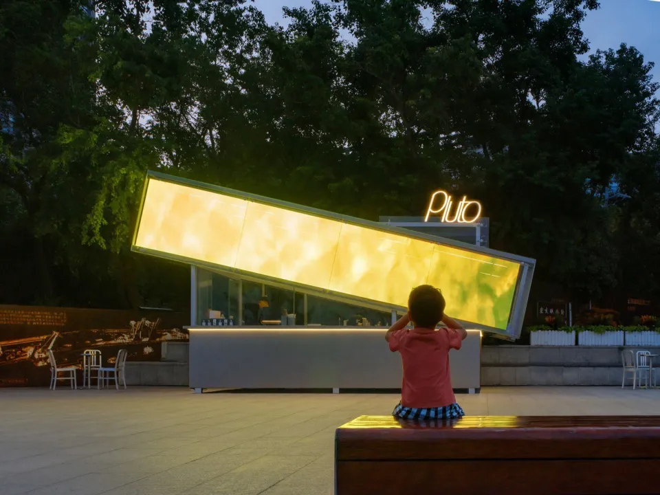 A child sits on a bench in front of a large yellow sculpture or artwork in a creative and engaging environment