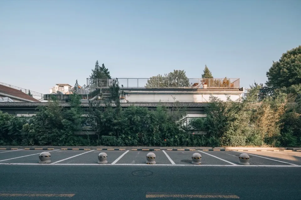 一座現代建築，配有金屬屋頂，周圍環繞停車場，有汽車與座椅，呈現公共或商業空間氛圍