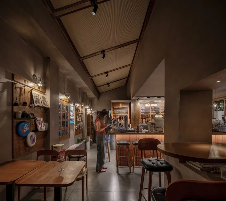 A lively restaurant scene with a modern design, wooden elements, and contemporary furnishings, featuring artworks on the walls and a mix of ambient and task lighting