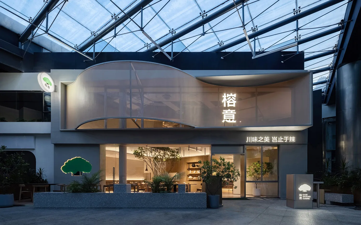 A modern Asian restaurant with glass walls, curved roof, and dining tables with potted plants, creating a comfortable and inviting atmosphere