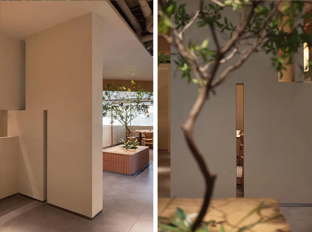 A restaurant interior with multiple dining areas, chairs, and a large tree, creating a cozy and inviting atmosphere