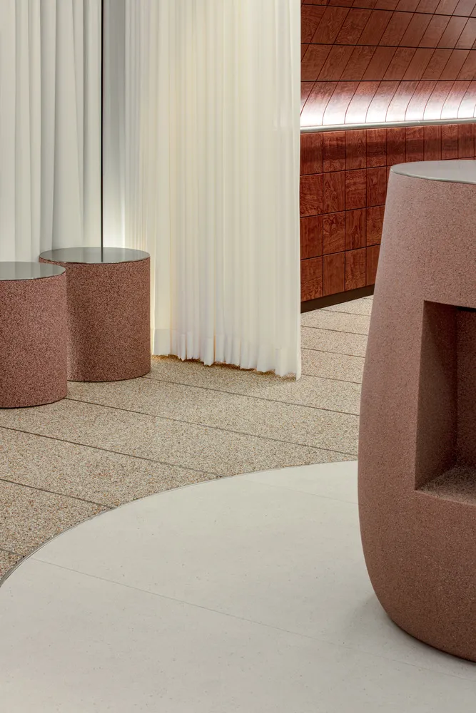 A large room with marble flooring, featuring three round tables and benches, in a modern and elegant atmosphere