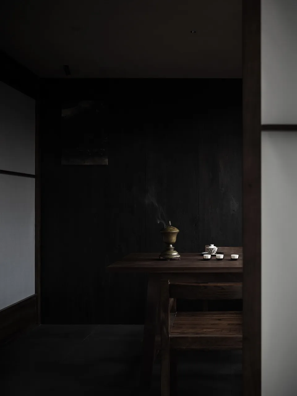 燈光柔和的餐廳，配有深色木桌、兩碗食物、杯子和花瓶，營造溫馨親密的氛圍