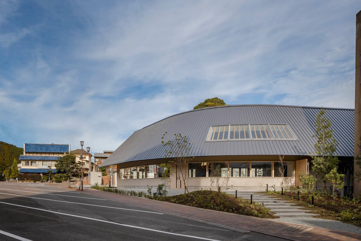 Modern building with a curved roof, brick and metal exterior, and large windows providing natural light