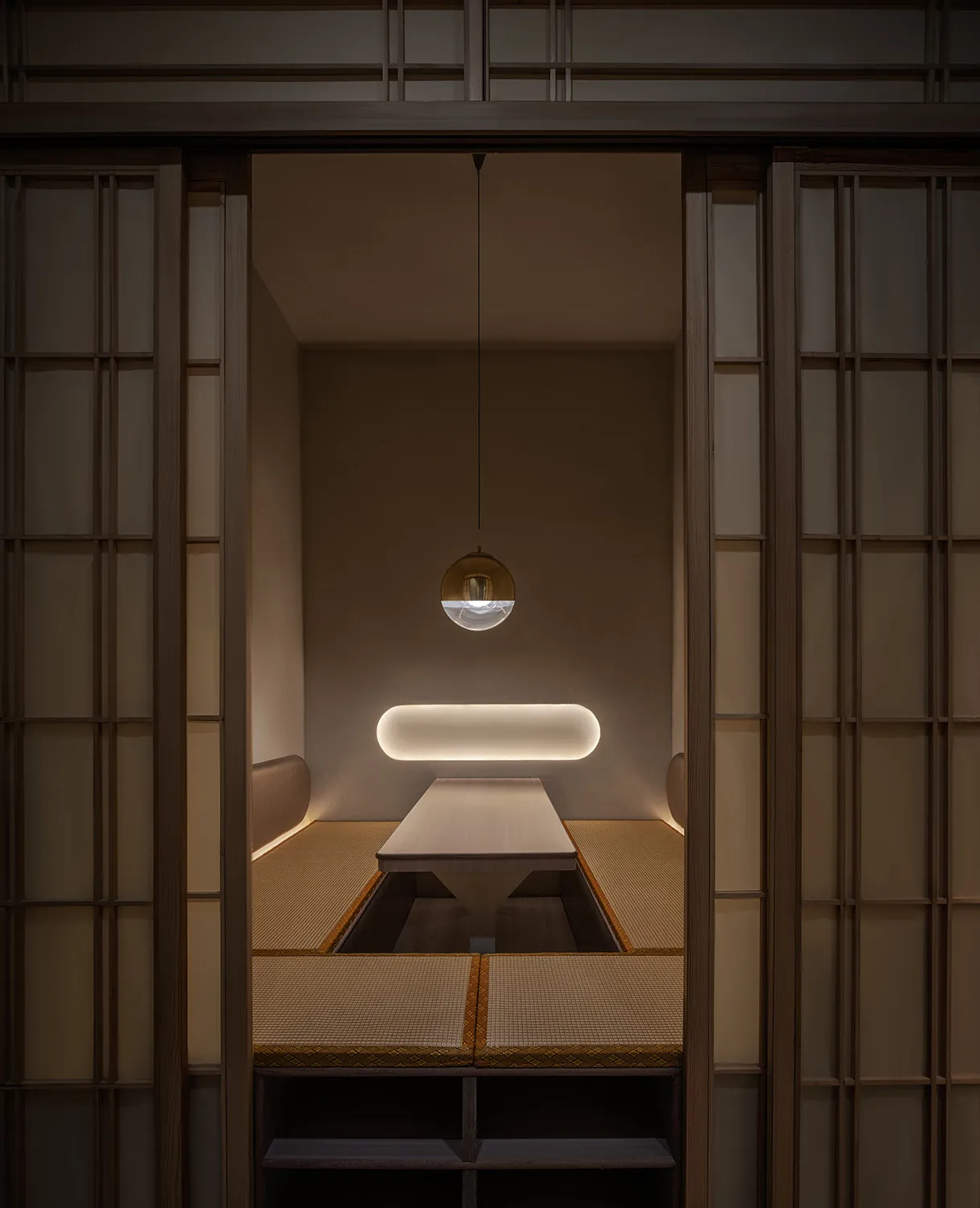 Dimly lit dining room with a symmetrical arrangement of chairs around a wooden table, creating a cozy atmosphere