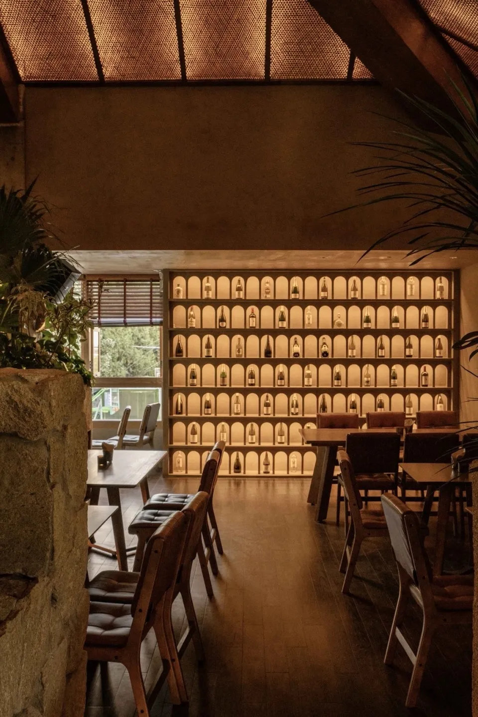 石牆陳列酒瓶的溫馨酒吧或餐廳區，舒適座椅與餐桌