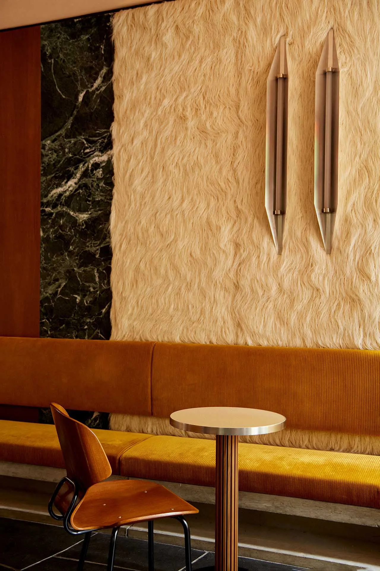 A warm and inviting living space with a yellow couch, furry wallpaper, two chairs, a dining table, and a vase, creating a cozy atmosphere