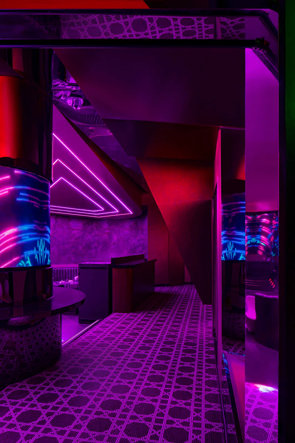 Purple-lit bar area with a wooden counter and two sinks, modern design