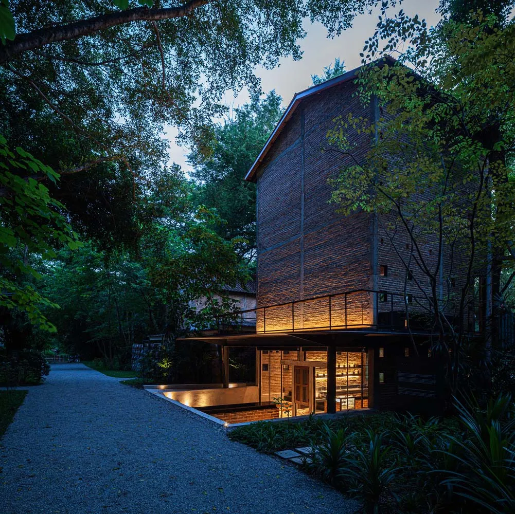 A brick house with a wooden structure and stone exterior, well-lit by artificial lights at night, with several windows for natural light