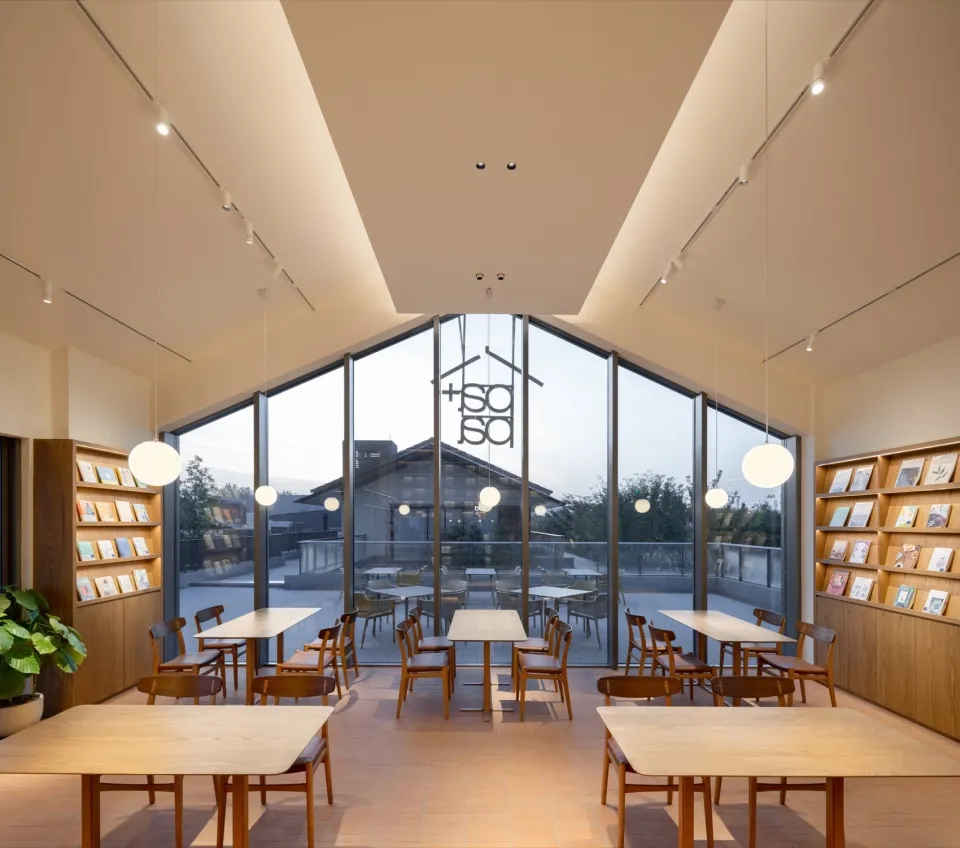 A calm and inviting library interior with wooden tables and chairs, multiple dining tables, and a comfortable atmosphere for reading and studying