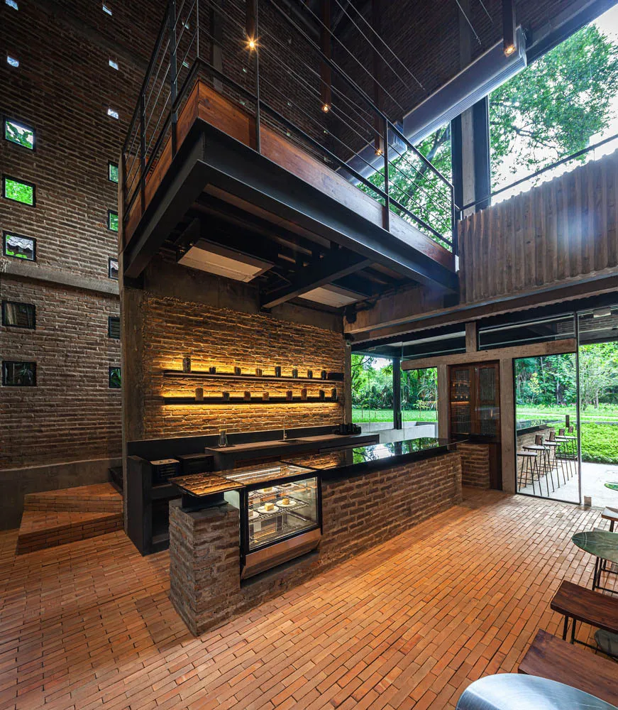 Rustic bar area with a brick counter, chairs, and a glass display case, creating an inviting atmosphere for socializing and dining