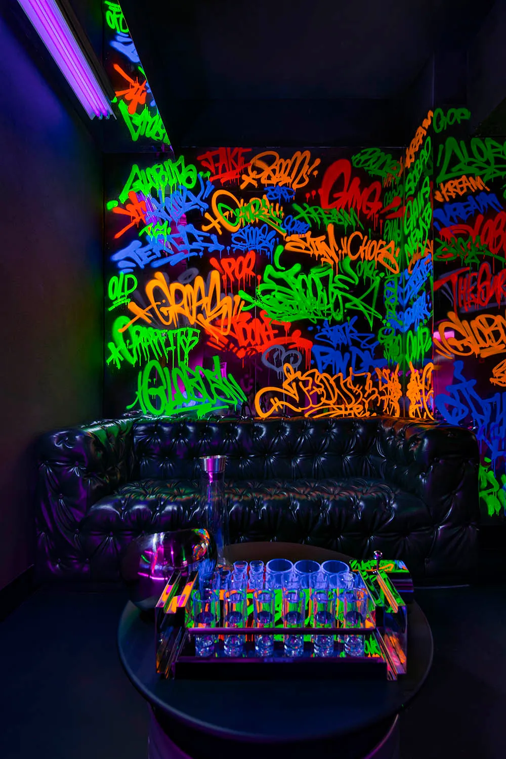 A modern living room with graffiti artwork, two couches, a chair, and a table with a vase and cup, creating a unique urban atmosphere