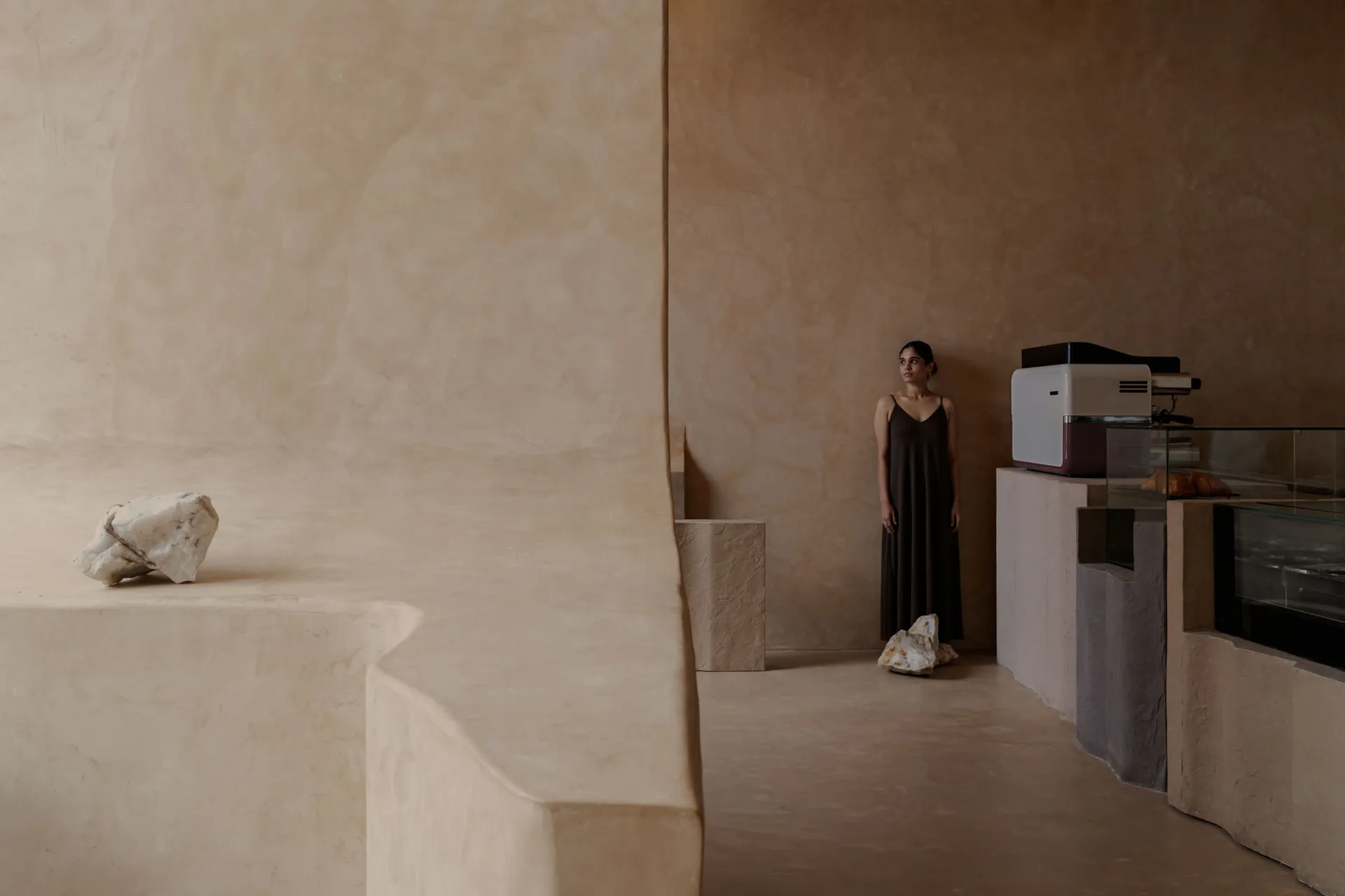 An empty room with a woman standing in front of a brown wall, creating a quiet and peaceful atmosphere
