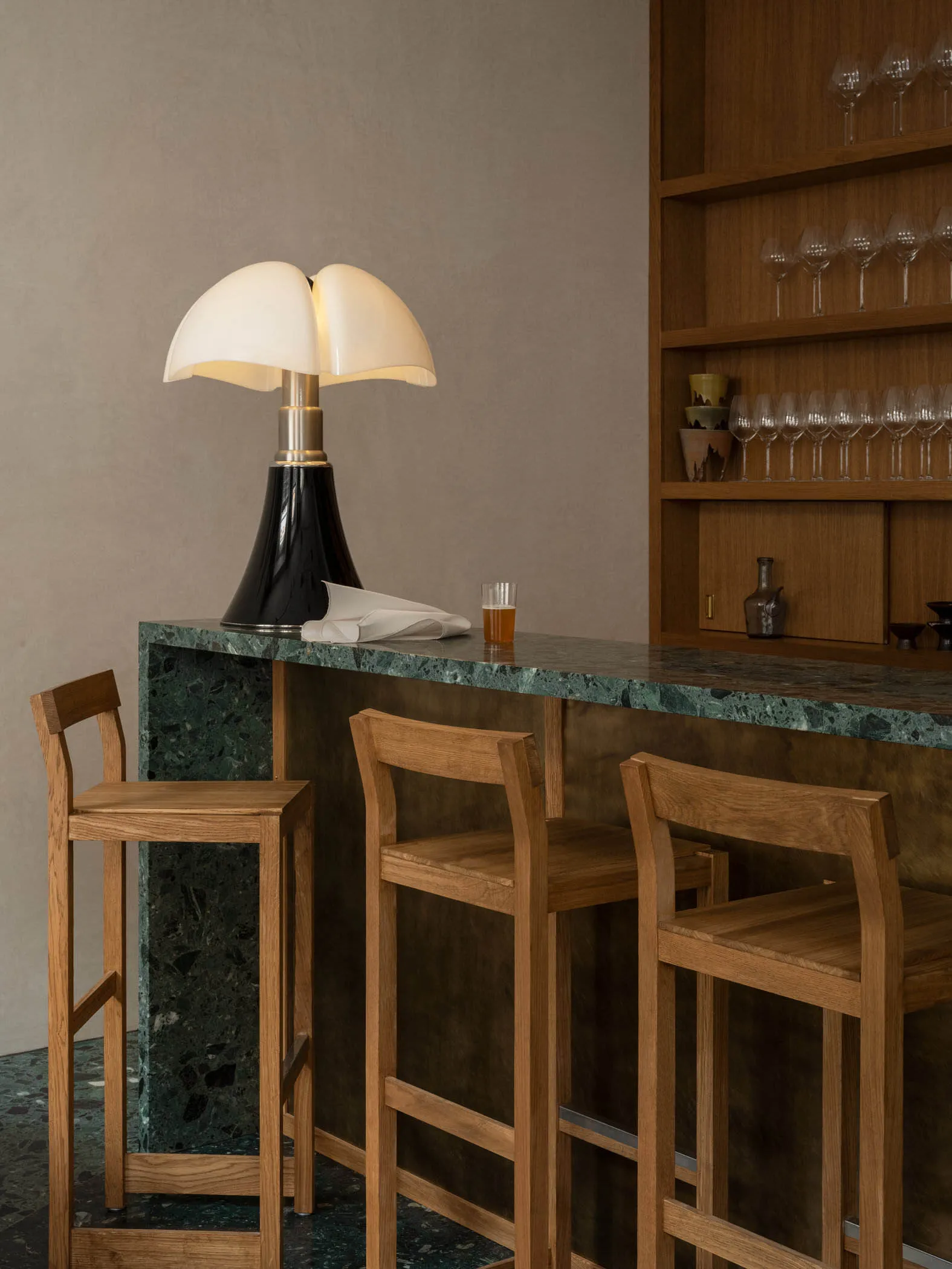 Inviting bar area with a marble countertop, wooden stools, and wine glasses, set in a stylish and sophisticated space