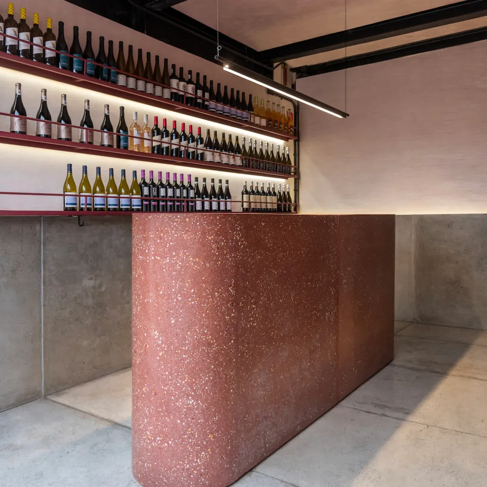 A sophisticated interior design showroom featuring a marble countertop with a display of wine bottles in various positions