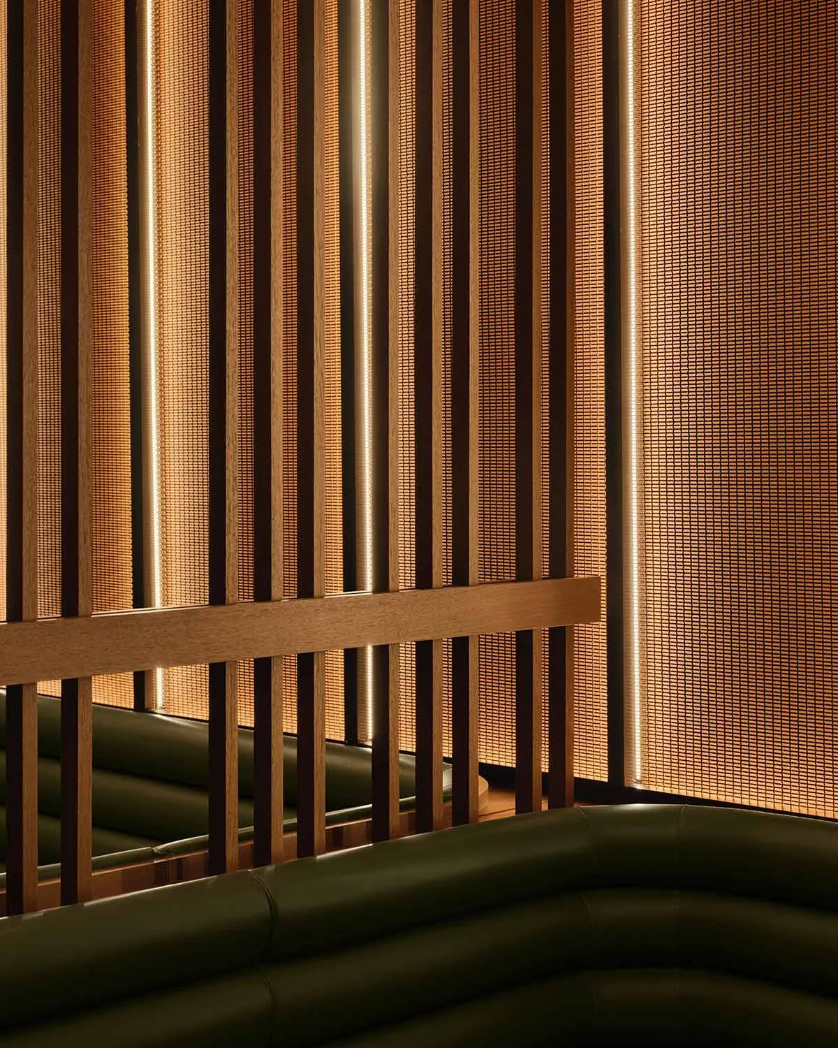 A modern living space with wooden walls and a green couch, featuring two couches and a warm inviting atmosphere