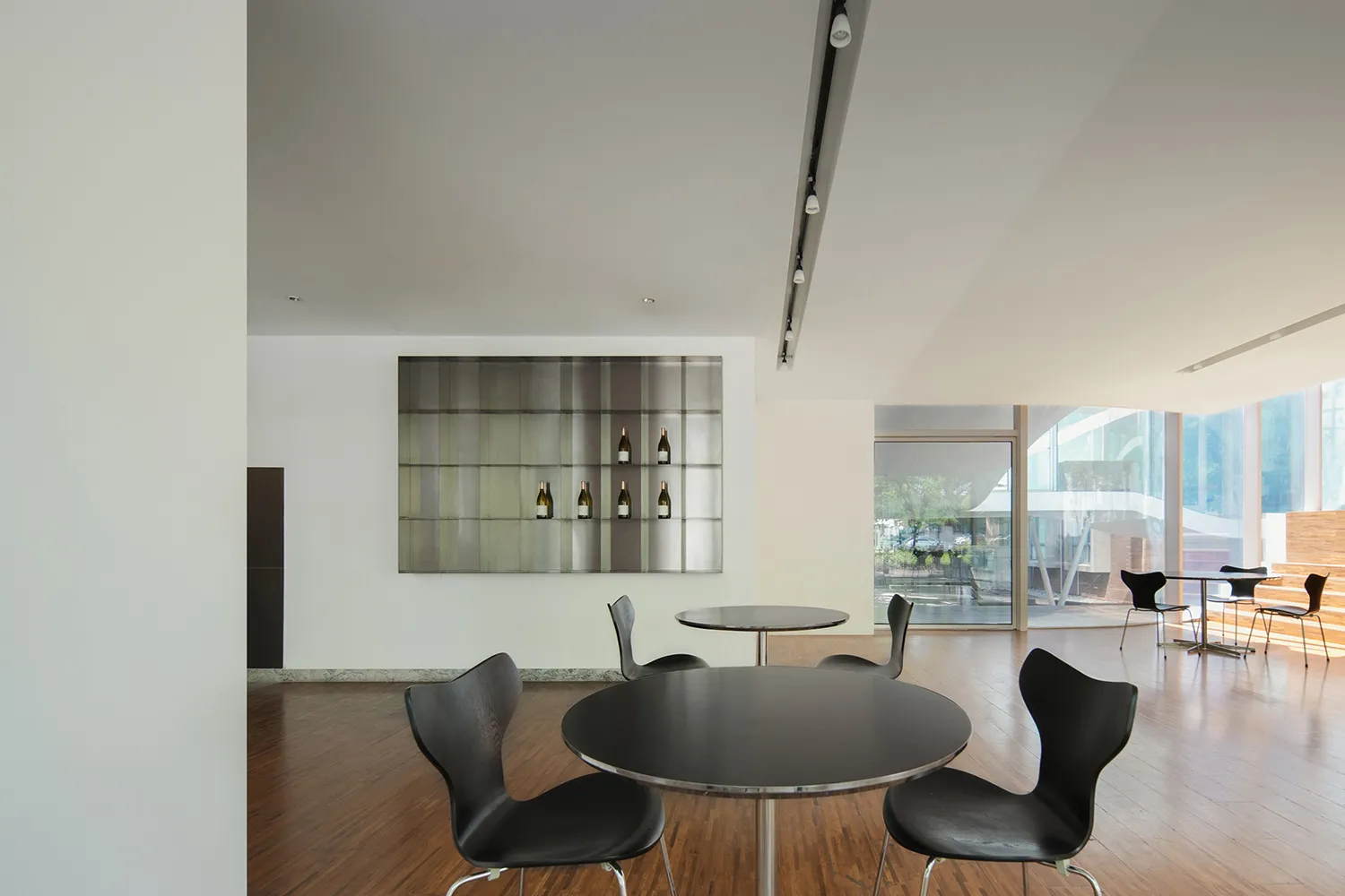 Dining area with a black table surrounded by modern chairs on a warm wooden floor