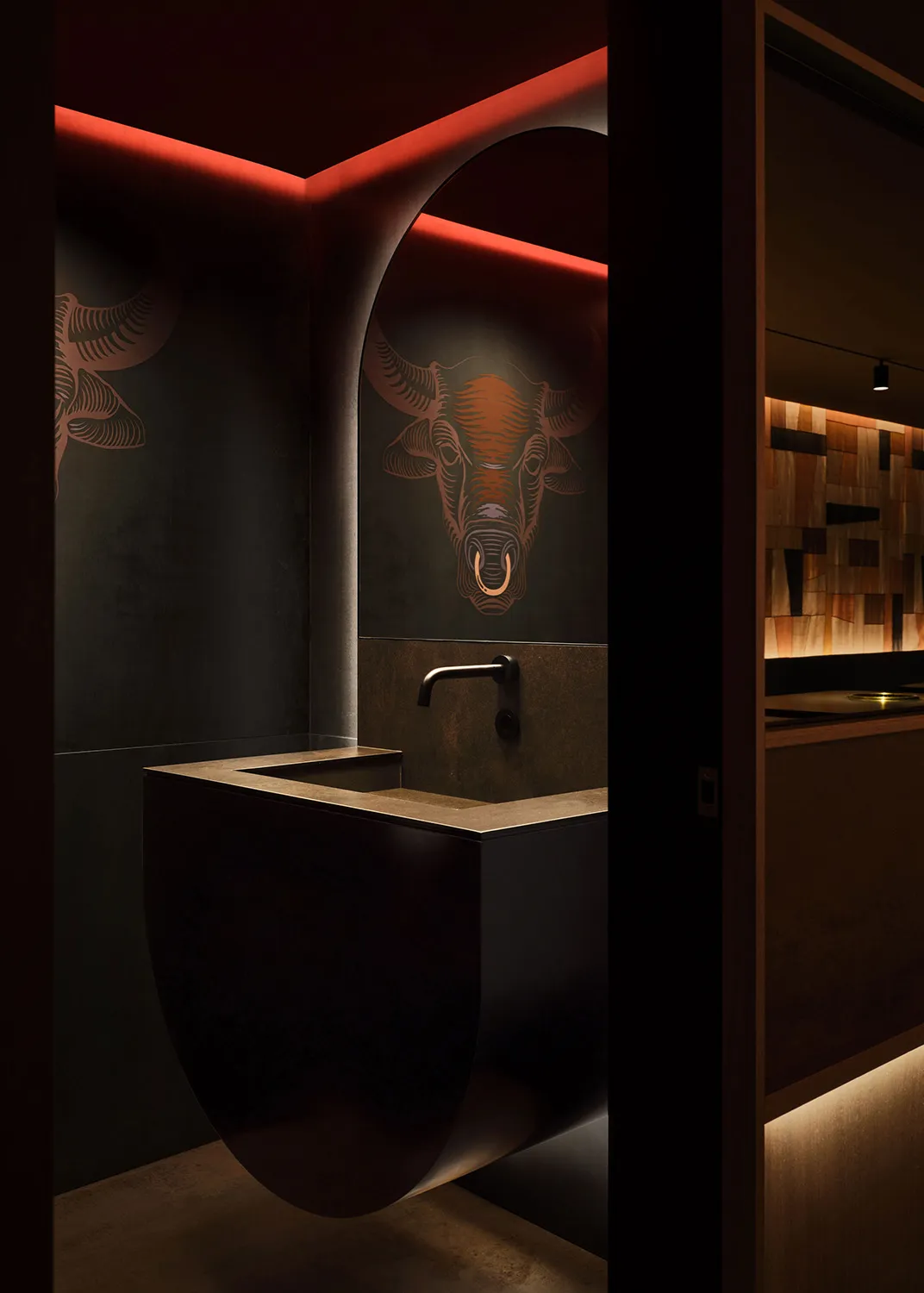 Bathroom with a sink, toilet, and decorative bull horns above the sink, set in a dimly lit space
