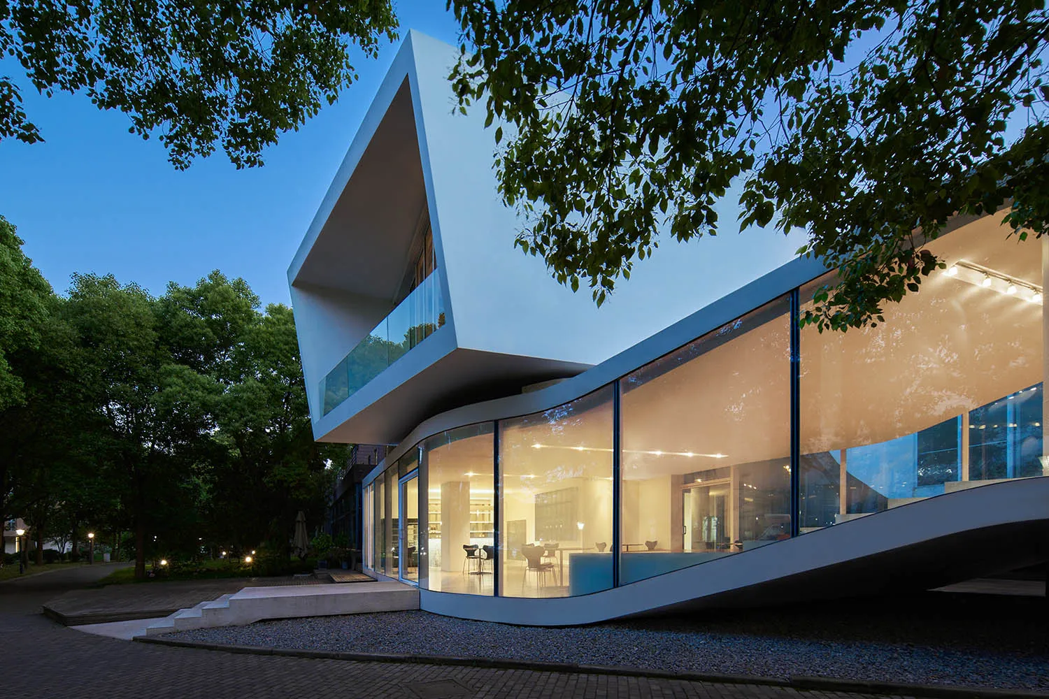 Modern building with curved design, large windows, and natural light, featuring glass and concrete materials