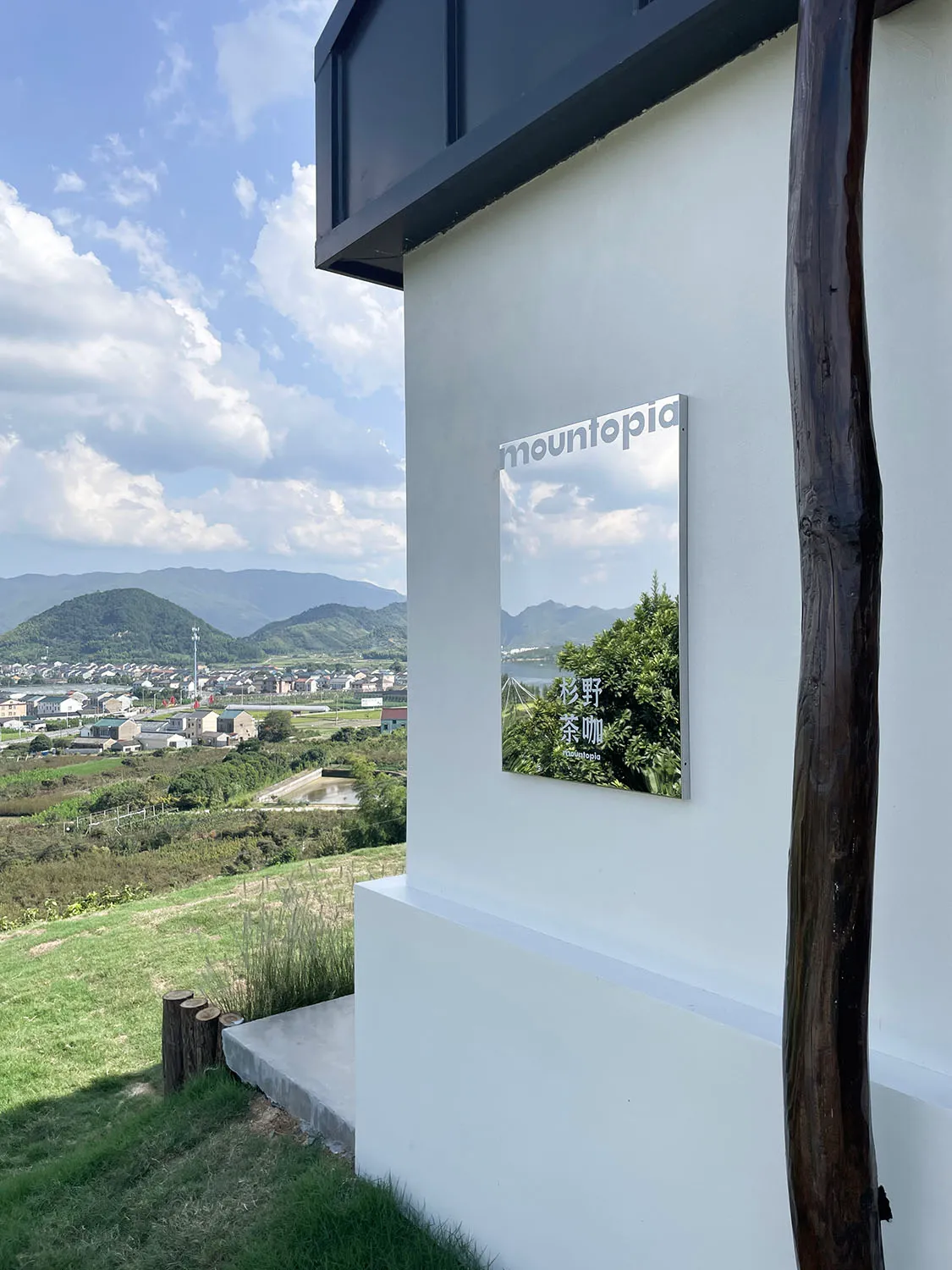 白色外觀的現代住宅位於山坡上，俯瞰山谷，背景有樹木