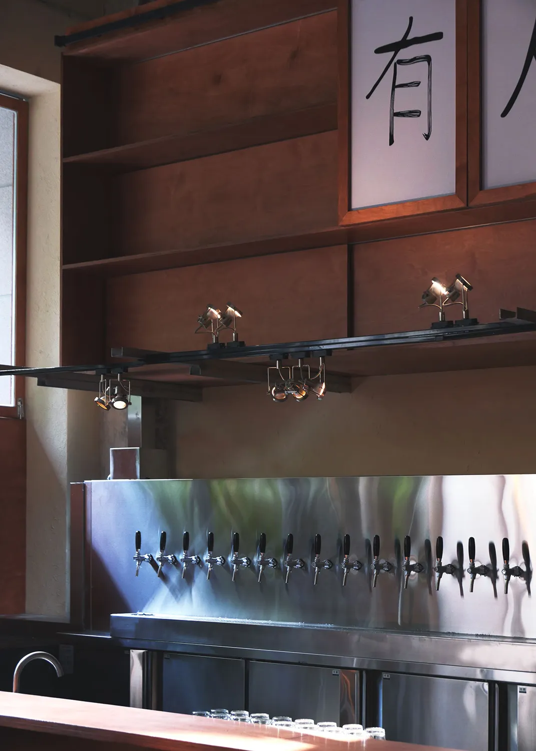 A modern bar area with stainless steel fixtures and a large number of beer taps mounted on the wall in a lively social environment