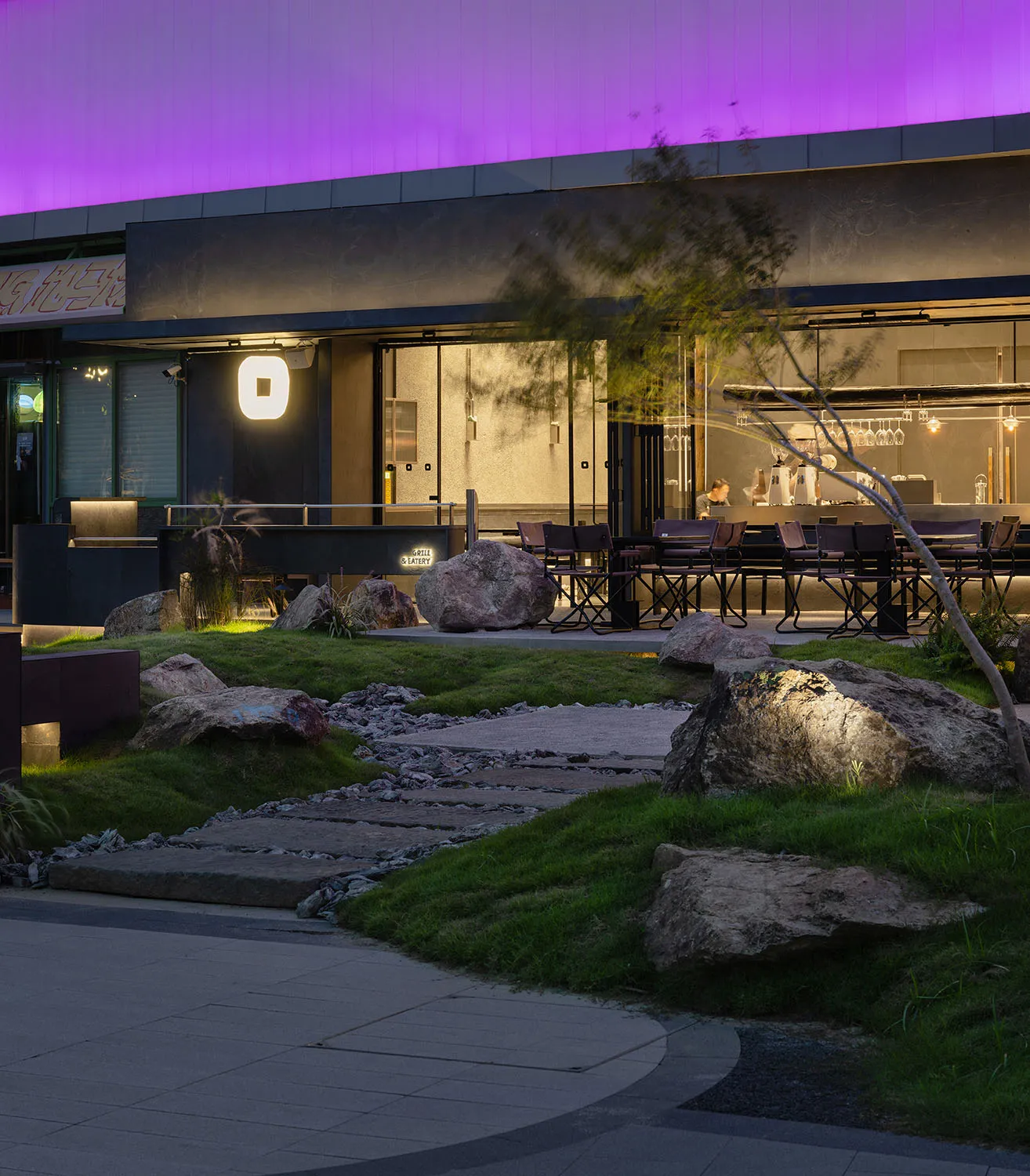 Outdoor restaurant area with patio seating, benches, and nearby trees creating a natural ambiance