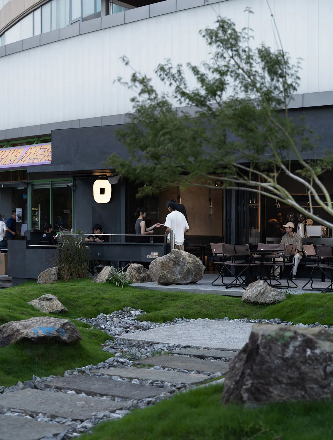 A restaurant patio with multiple chairs and tables, potted plants, and umbrellas, creating a comfortable and inviting atmosphere