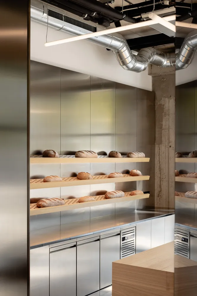 Industrial bakery with wooden racks filled with a diverse selection of bread, displayed in a clean and organized manner