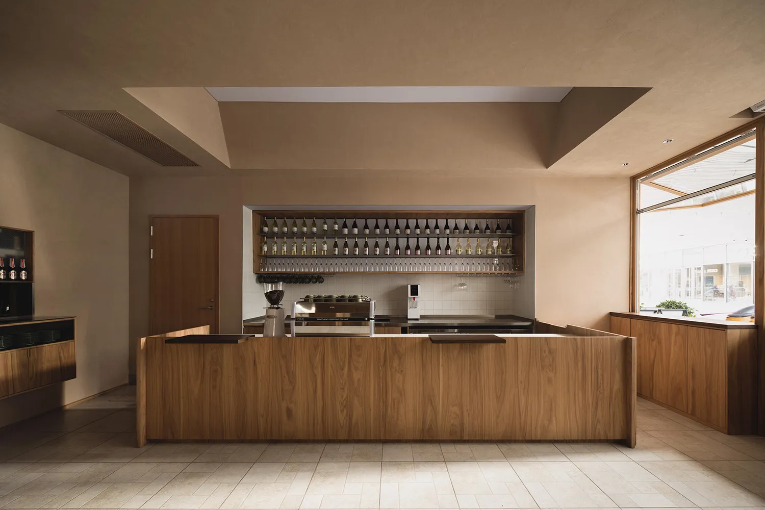 A restaurant bar area with wooden floors and walls, featuring bottles on the countertop, creating a warm and welcoming atmosphere for socializing and dining