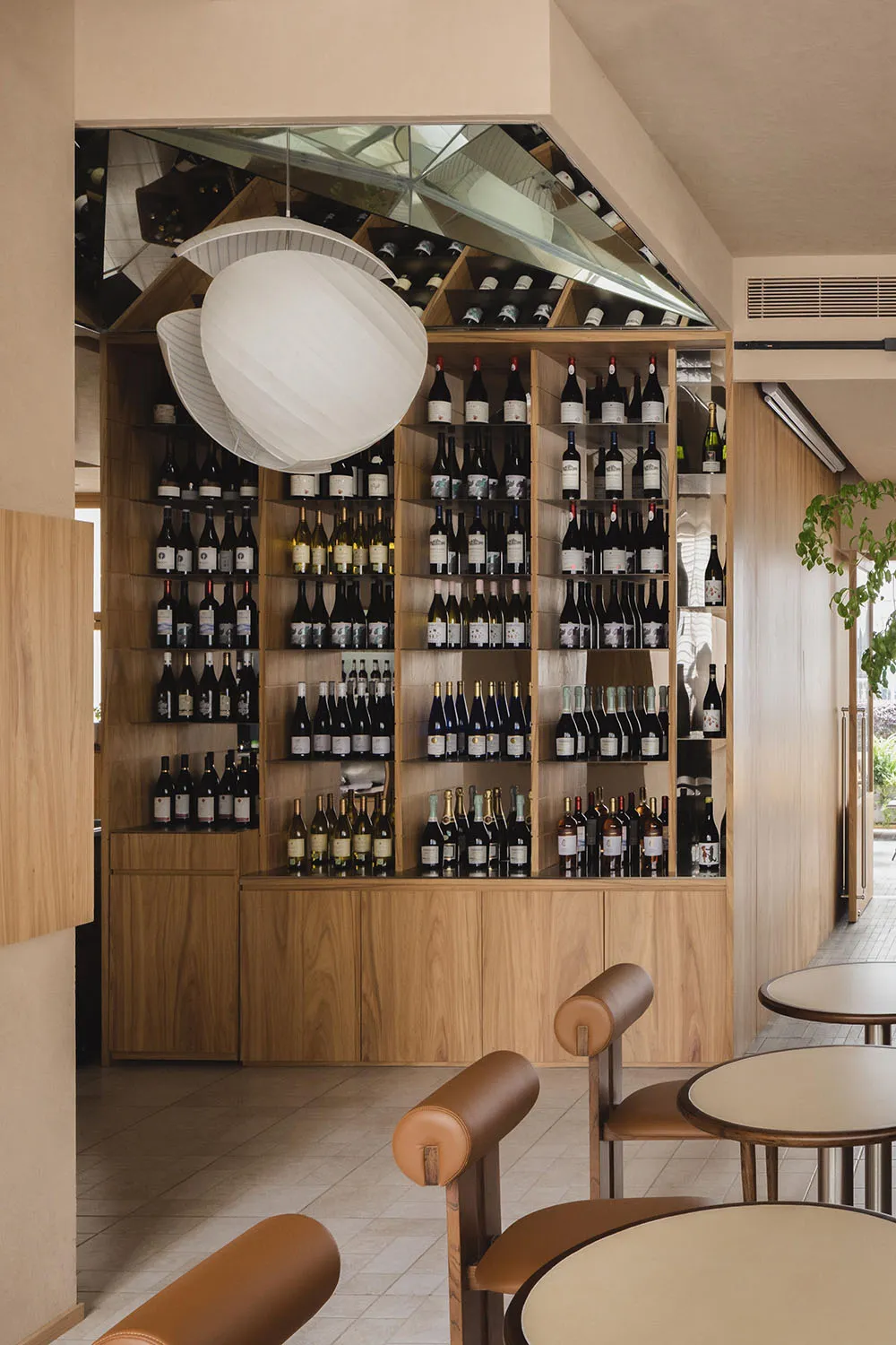 Cozy restaurant interior with wooden walls and floors, wine bottles on shelves, and seating areas for guests