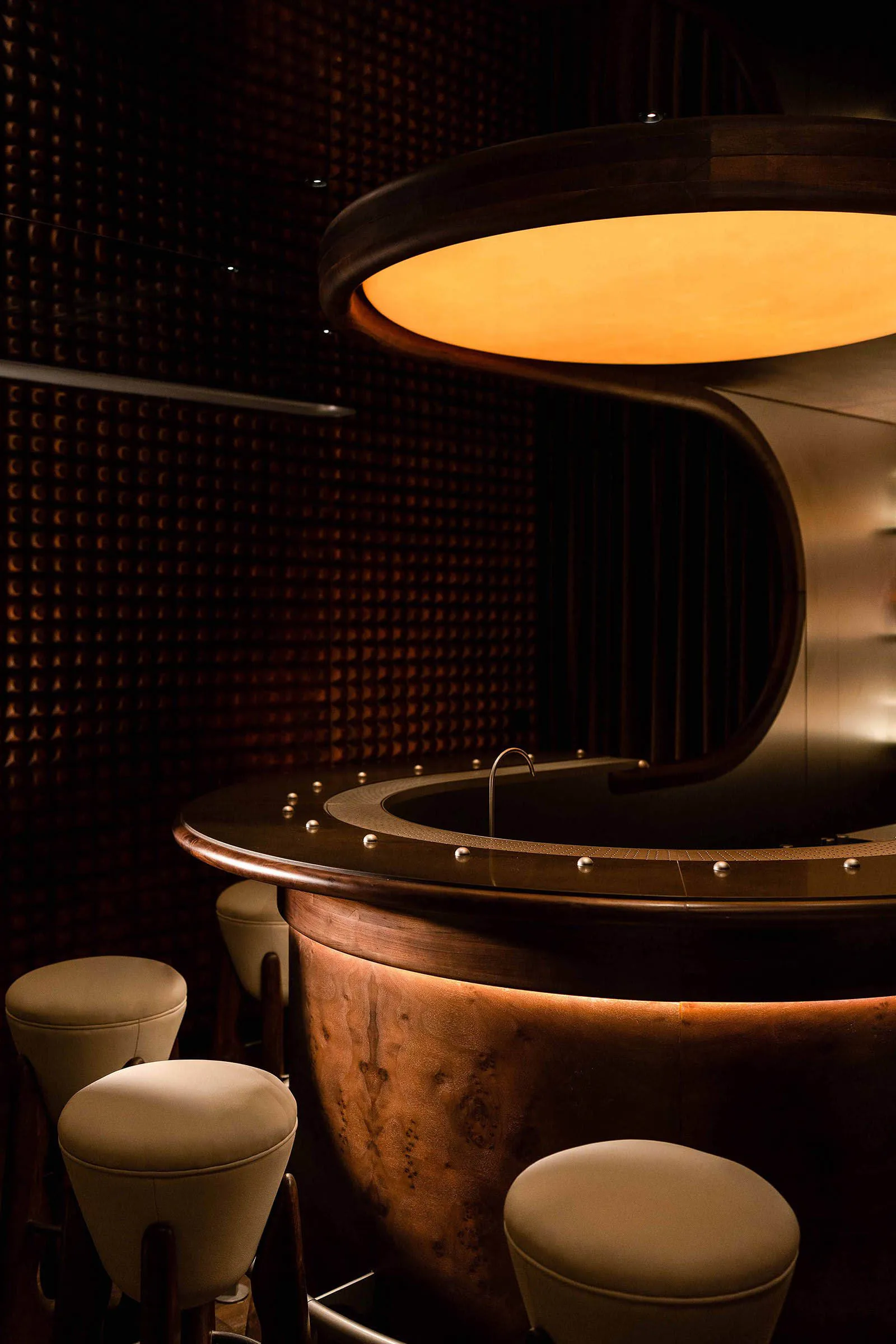 Elegant bar area with a large wooden countertop, sink, and two chairs, featuring a modern and sophisticated design with warm and inviting atmosphere