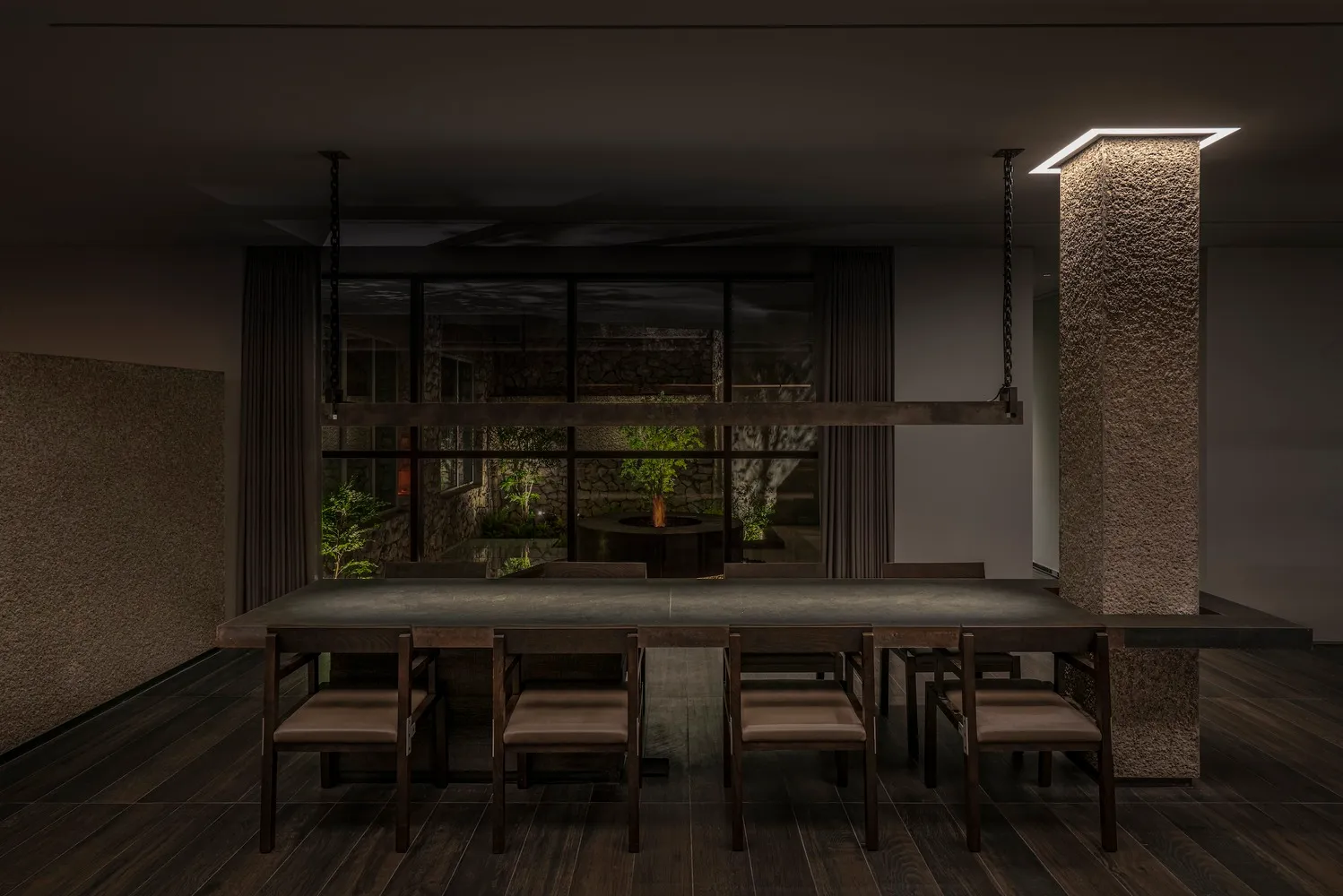 A well-lit dining area with a large wooden dining table surrounded by multiple chairs, creating a comfortable atmosphere for meals and gatherings