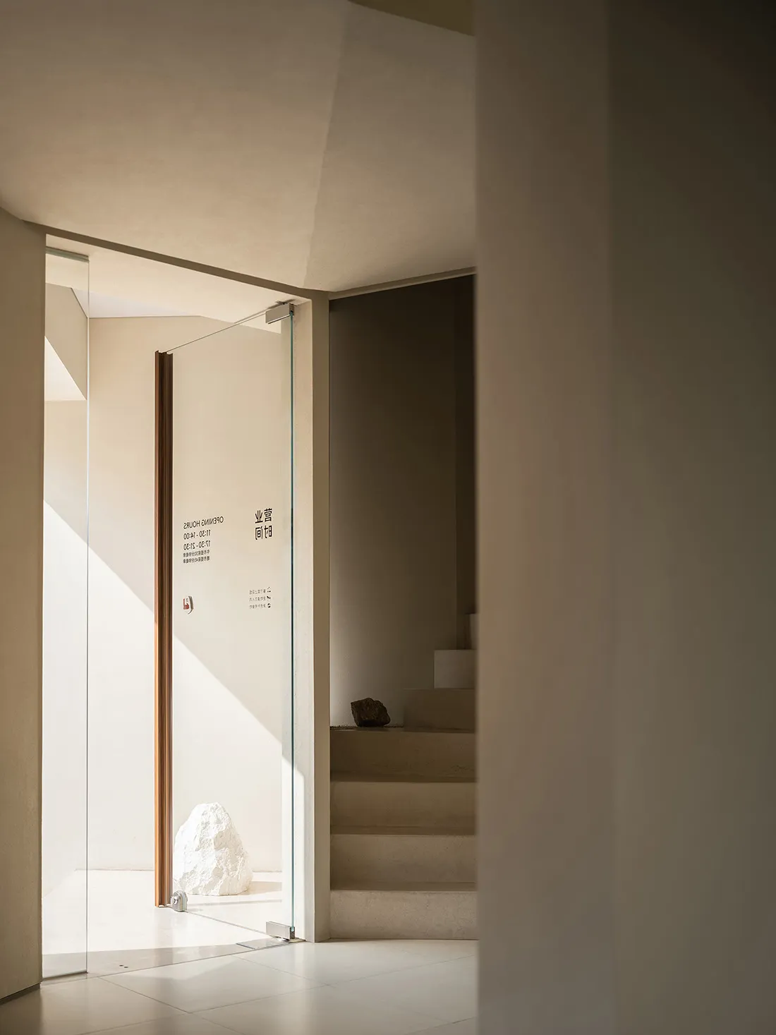 Industrial style hallway with concrete walls, glass door, and staircase, conveying a sense of depth and organization