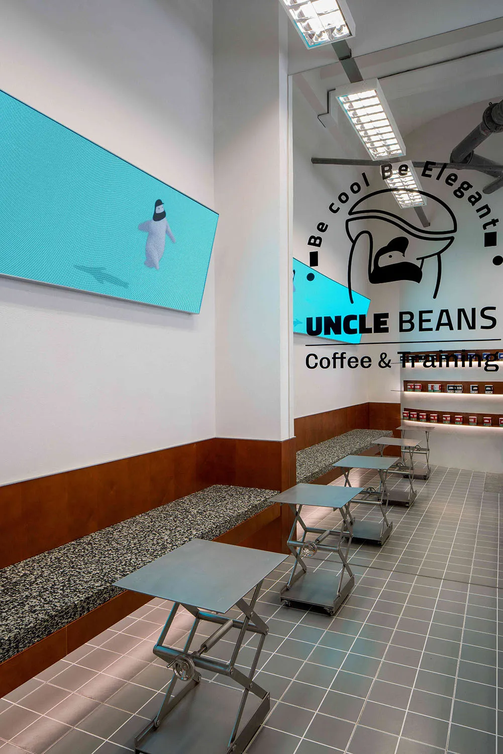 A modern coffee shop with brown and white walls, benches, and a large TV mounted on the wall, creating a warm and inviting atmosphere